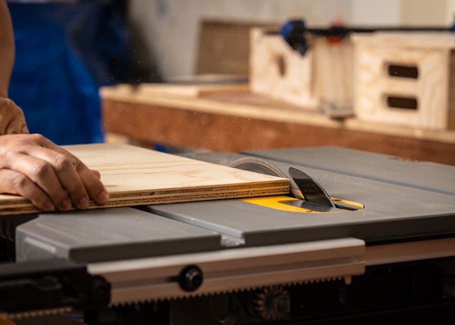 Hands guiding a board through a table saw cut