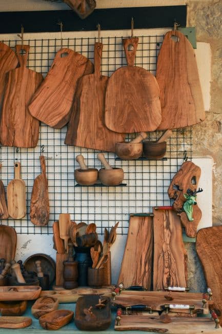 Handmade wooden cutting boards and kitchen utensils hanging on a display grid in a craft shop