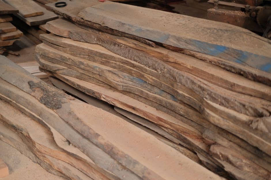 A stack of rough sawn hardwood planks lying on a workshop bench