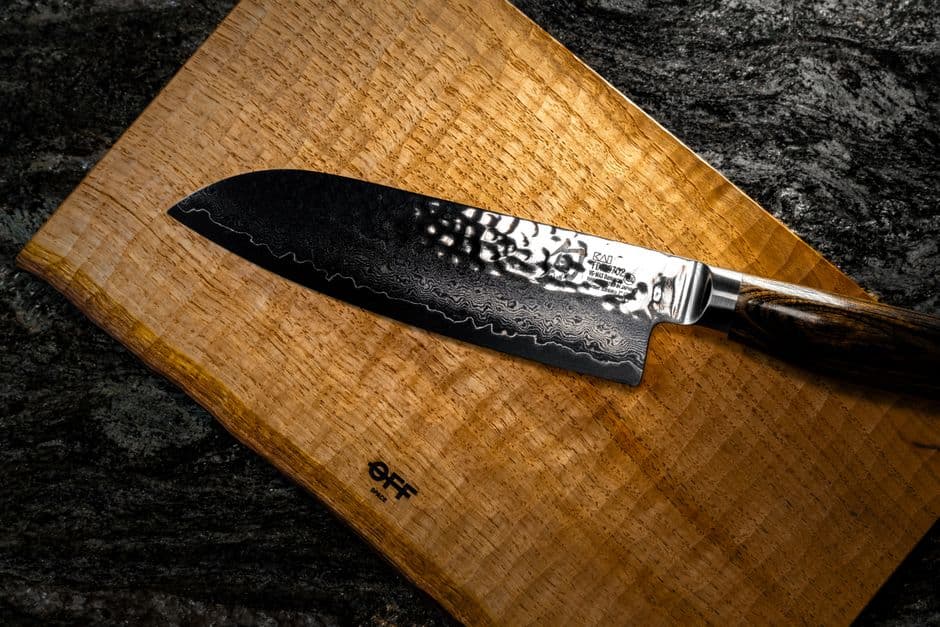 A Santoku knife lying on a figured wooden cutting board