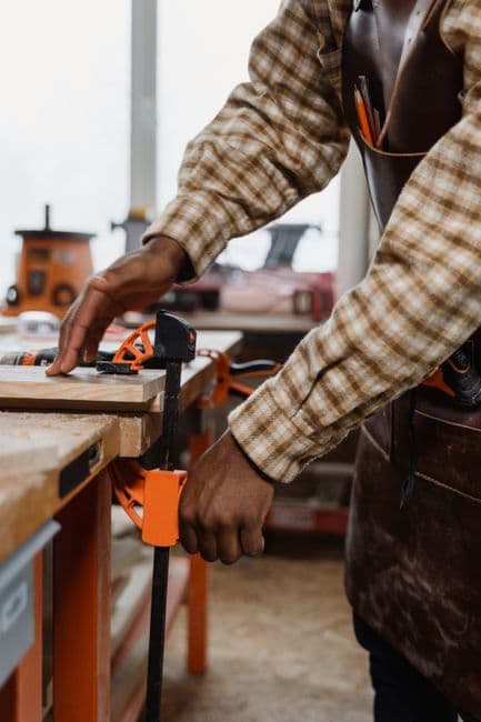 A woodworker tightening a clamp on a workpiece at the bench